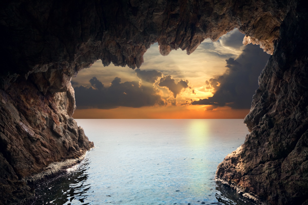 Sea cave opening to a tranquil ocean and sunset sky, a beautiful wallpaper or canvas print.