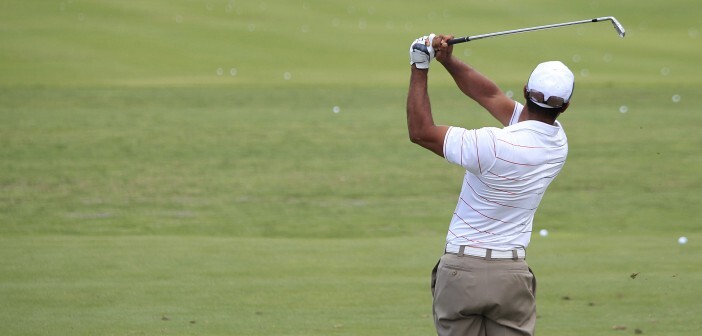Golfer Tiger Woods mid-swing on a green golf course, perfect for a custom wallpaper.