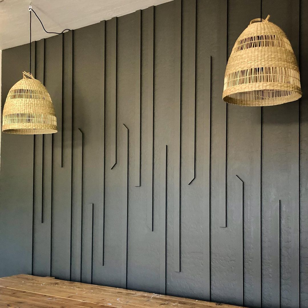 A modern accent wall with vertical wooden slats and two wicker pendant lights, suitable for custom wallpaper.