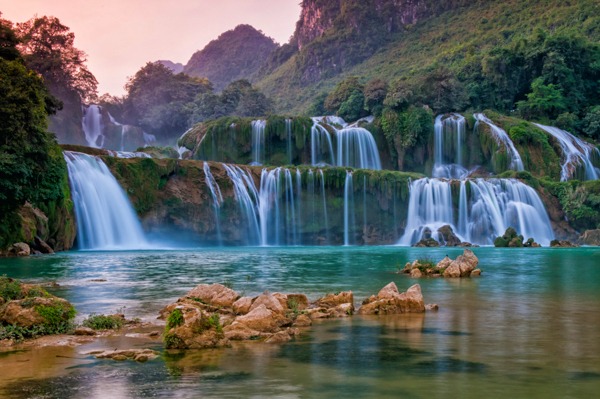 Majestic waterfall wall mural and clear lake in a stunning custom wallpaper design.