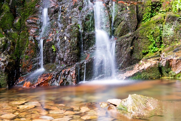 Close up of a natural waterfall wallpaper design with mossy rocks and clear water.